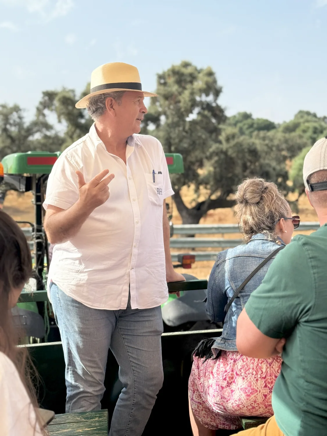 Guide en chapeau de paille commentant une visite pour un groupe, en pleine campagne