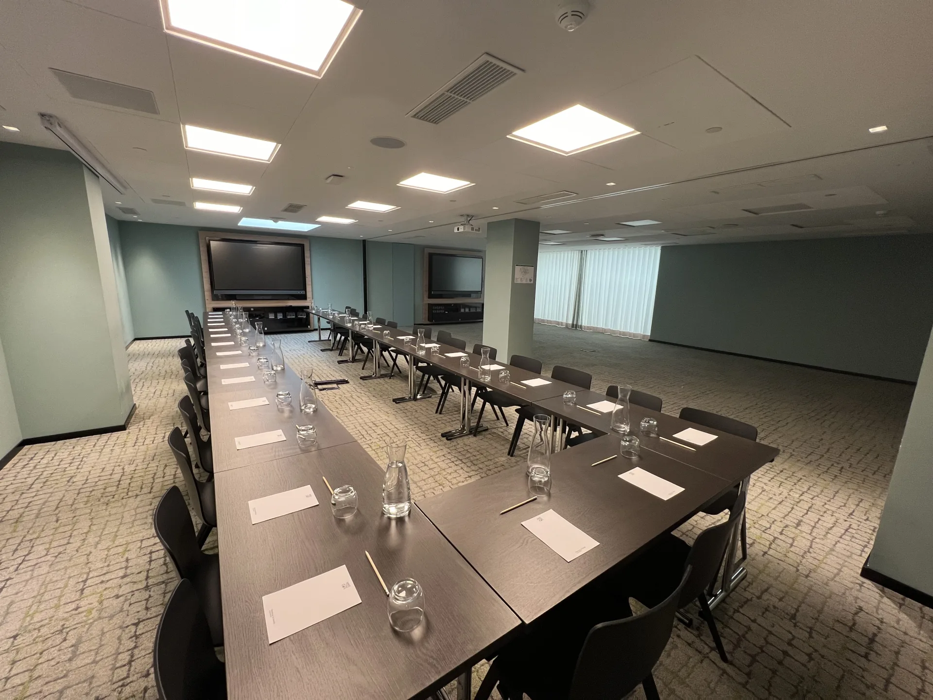 Salle de réunion en U équipée d’un écran, prête pour un séminaire