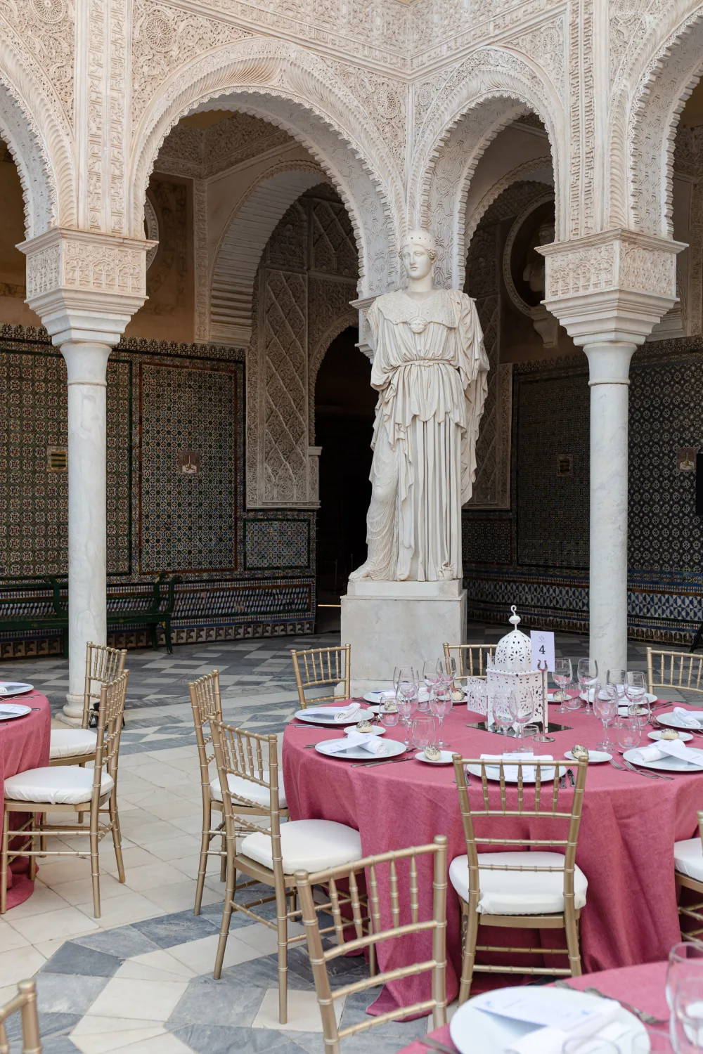 Tables rondes fuchsia dressées dans un patio à colonnes