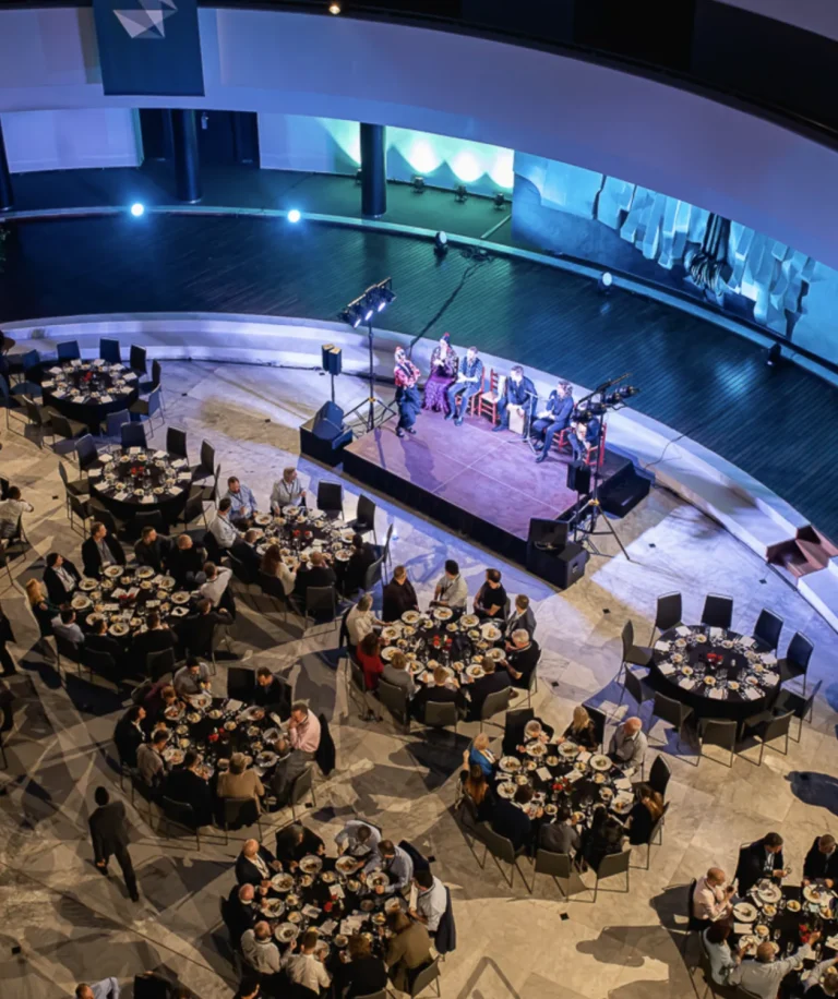 Vue plongeante sur une salle de spectacle et ses tables rondes pendant un dîner-show