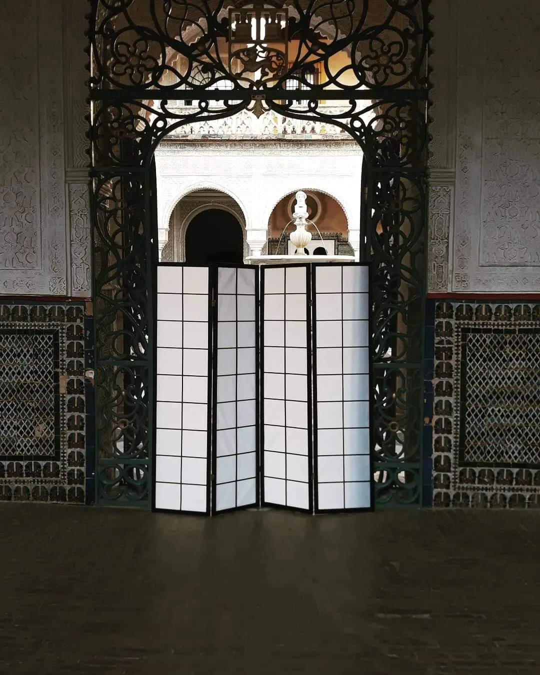 Paravent lumineux dressé sous une arche en fer forgé