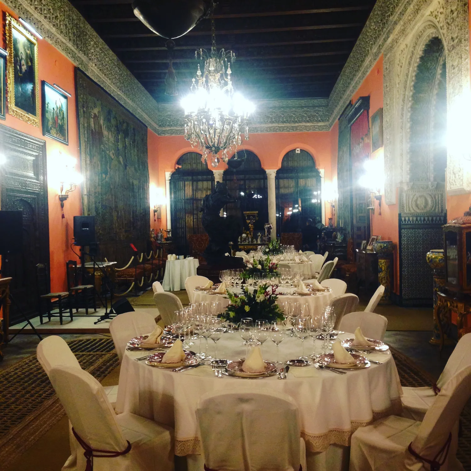 Salon d’apparat aux murs orangés, tables dressées sous un lustre