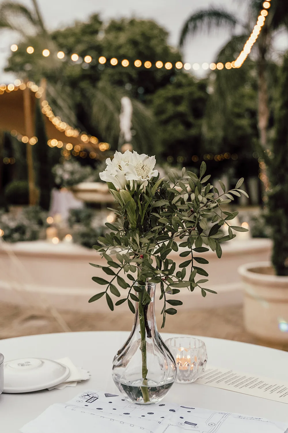 Table dressée avec un bouquet blanc sous des guirlandes lumineuses