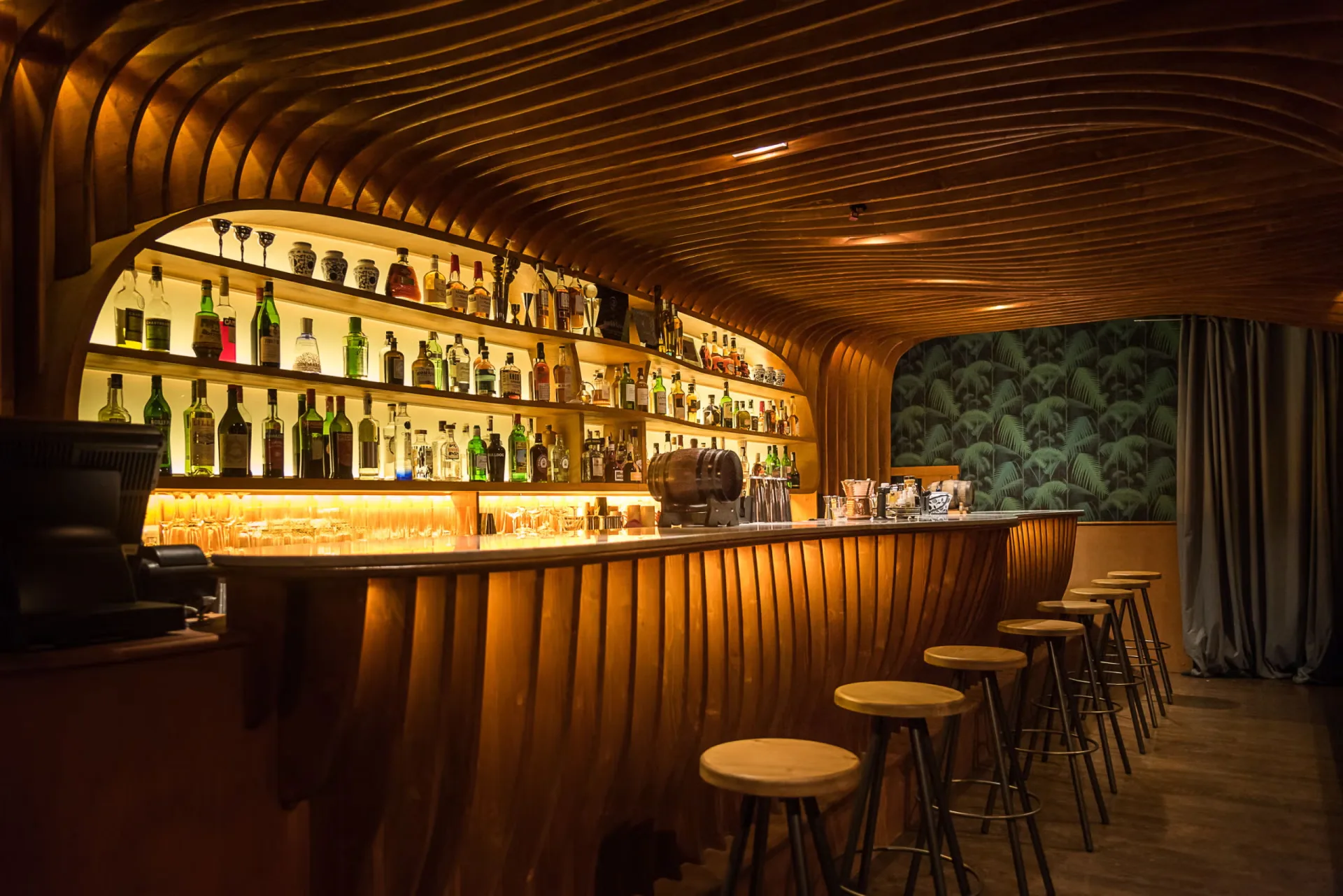 Bar d'hôtel au comptoir de bois courbe et lumière ambrée