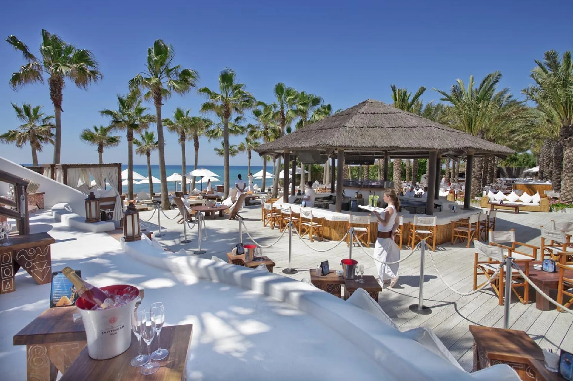Lits balinais blancs et parasols autour d'une piscine