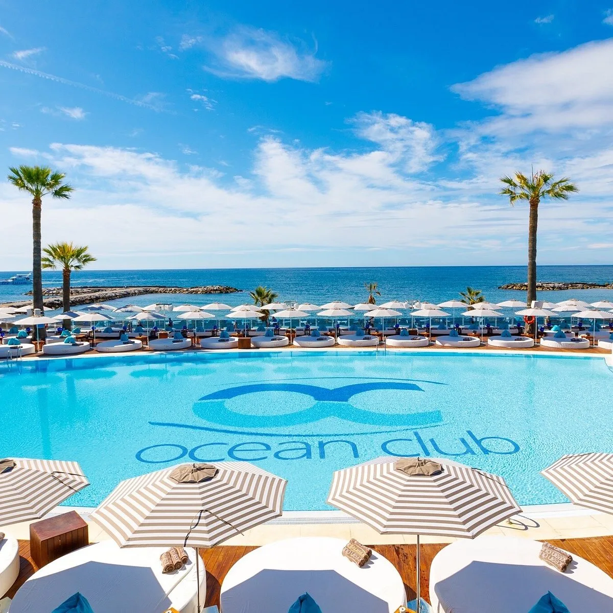 Piscine bordée de parasols rayés dans un beach club de Marbella