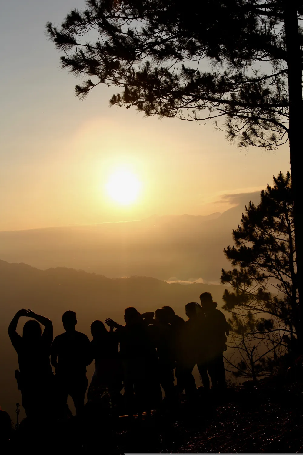Groupe en silhouette face au coucher de soleil au sommet d'une colline