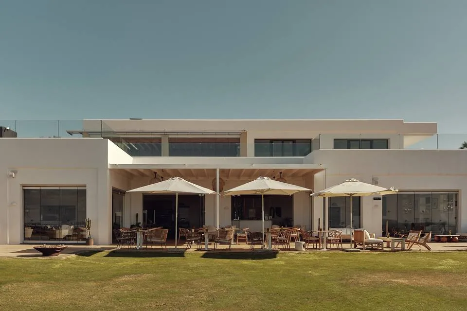 Villa contemporaine blanche et sa pelouse, parasols ouverts
