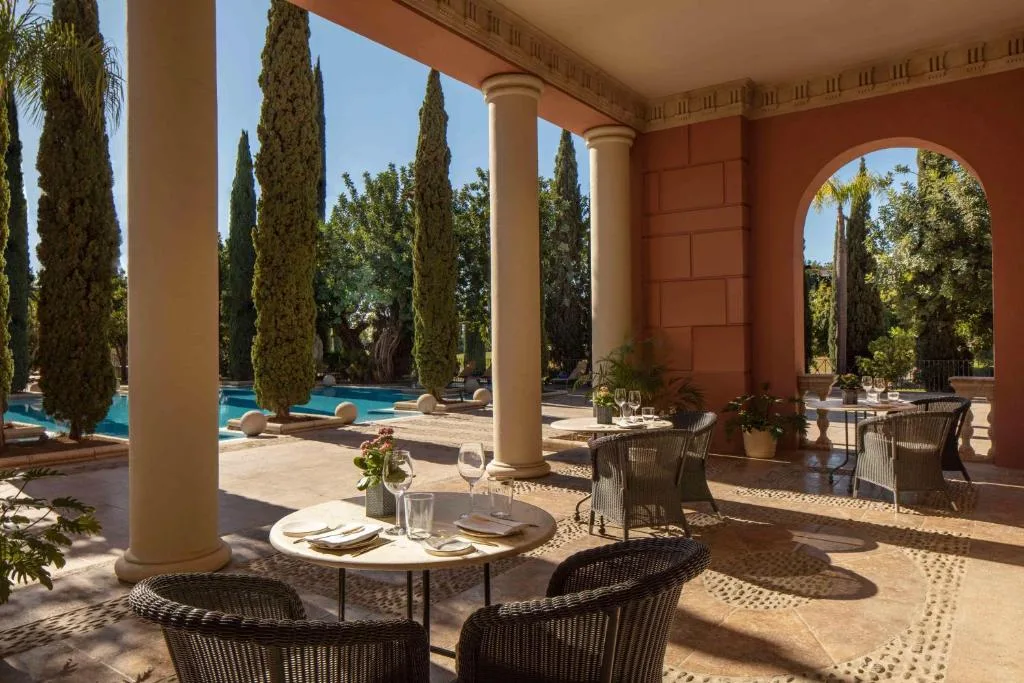 Patio à colonnes bordé de cyprès, tables dressées à l'ombre